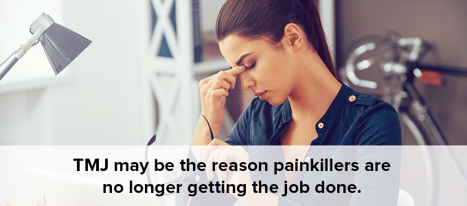 Woman having a hard time working because of pain caused by TMJ disorder.